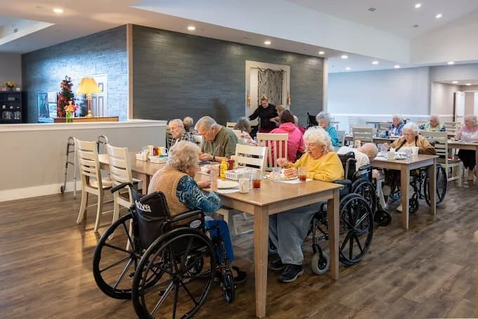 A group of older adults sitting around a few tables in a senior living community.