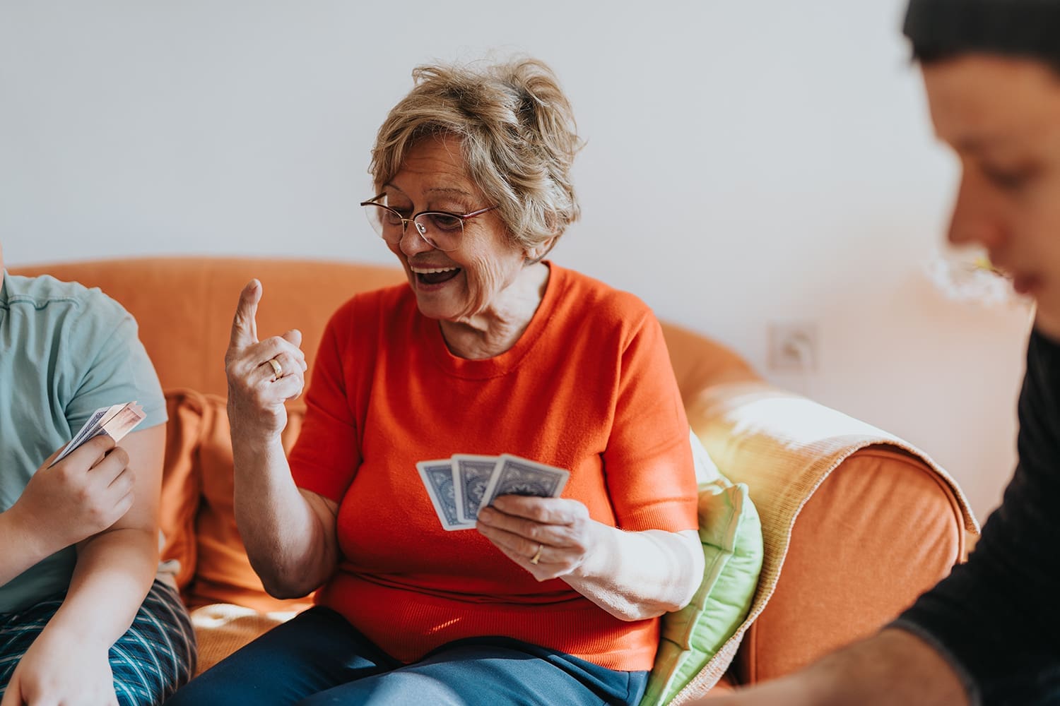 An older woman in an orange shirt playing a card game.