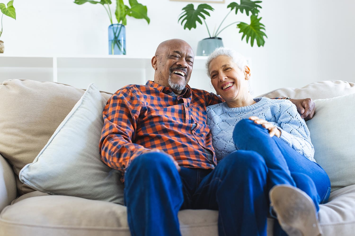 Two smiling older adults on a couch.